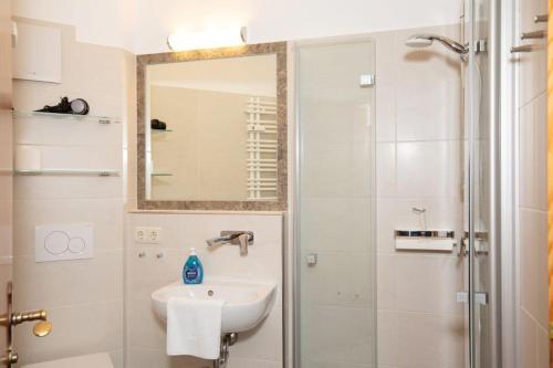 een badkamer met een wastafel en een douche met een spiegel bij Ferienwohnung Rosendahl in Reit im Winkl