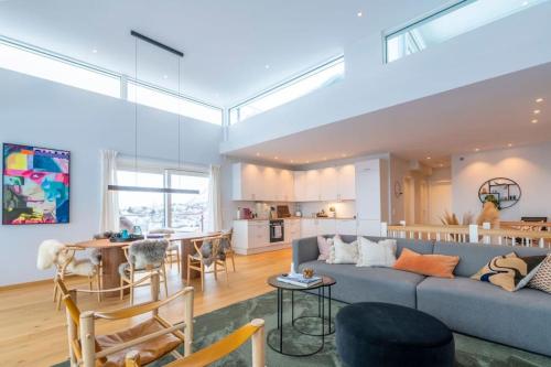 ein Wohnzimmer mit einem blauen Sofa und einer Küche in der Unterkunft Leilighet med sjøutsikt og privat takterrasse. Parkering in Svolvær