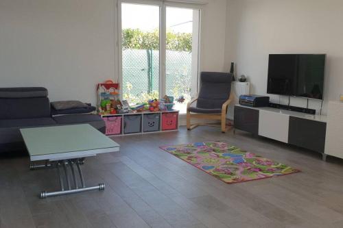 ein Wohnzimmer mit einem Sofa und einem TV in der Unterkunft Maison moderne proche site JO, Paris et Disneyland in Ferrières-en-Brie