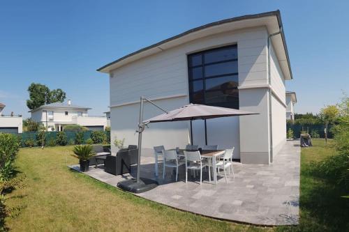 eine Terrasse mit einem Tisch, Stühlen und einem Sonnenschirm in der Unterkunft Maison moderne proche site JO, Paris et Disneyland in Ferrières-en-Brie