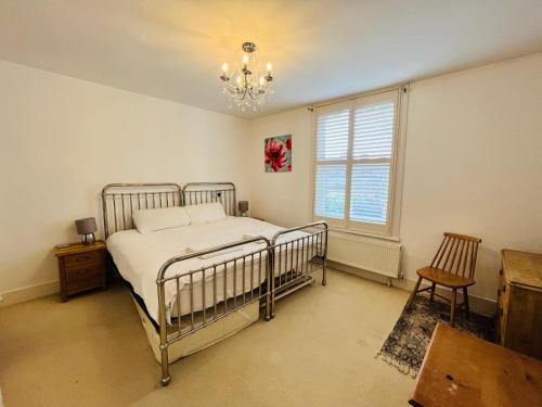 a bedroom with a bed and a window and a chandelier at Luna Cottage - Grove Road Cottages in Stratford-upon-Avon