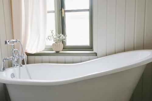 a white bath tub in a bathroom with a window at Avar ja hubane stuudiokorter kesklinnas in Viljandi