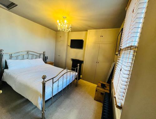 - une chambre avec un lit et un lustre dans l'établissement Simpsons Cottage - Grove Road Cottages, à Stratford-upon-Avon