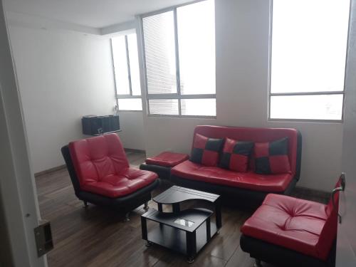 a living room with two red chairs and a table at Apartamento en Villavicencio in Villavicencio