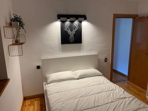 a bedroom with a white bed with a picture on the wall at Apartamento con encanto (Taüll) DEER 1 in Taüll