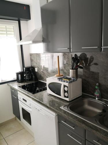 un comptoir de cuisine avec un micro-ondes et un évier dans l'établissement 60m2 à 300m de la plage - 6 pers - linge compris - Wifi gratuit, à Berck-sur-Mer