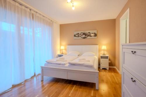 a bedroom with a bed with white sheets and pillows at Chalet Apartments Iseltwald in Iseltwald