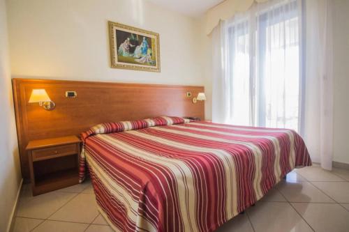 a bedroom with a bed with a striped blanket and a window at Hotel Jolly in Modugno