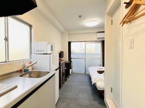 a small kitchen with a sink and a refrigerator at GR HONKAWA - Global Resort Hotel in Hiroshima