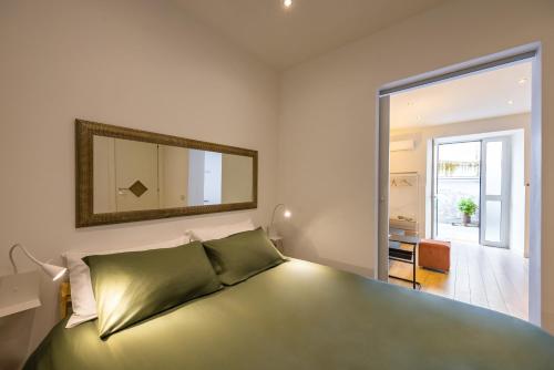 una camera da letto con un letto verde con uno specchio sul muro di Corte Belvedere a Napoli