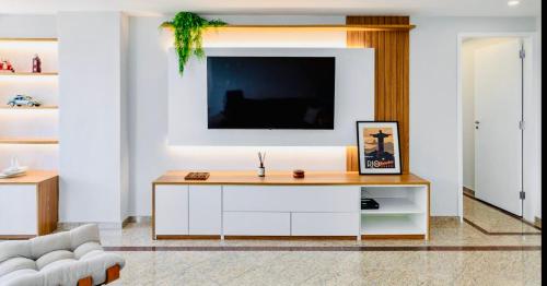 a living room with a tv on a white wall at Maravilhoso apartamento na orla da Barra da Tijuca in Rio de Janeiro