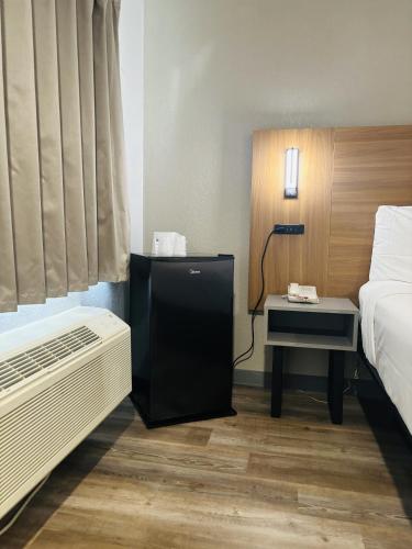 a hotel room with a bed and a night stand with a table at Motel 6-Santa Ana, CA in Santa Ana