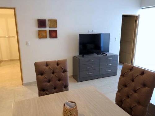 a living room with a table and two chairs and a television at Bahia del Tezal 103b, 1BR Modern condo big rooftop pool walk to beach through Riu hotel in Cabo San Lucas