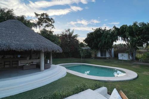 una piscina in un cortile con tetto di paglia di Beautiful resting home, near Las Estacas a Yautepec de Zaragoza