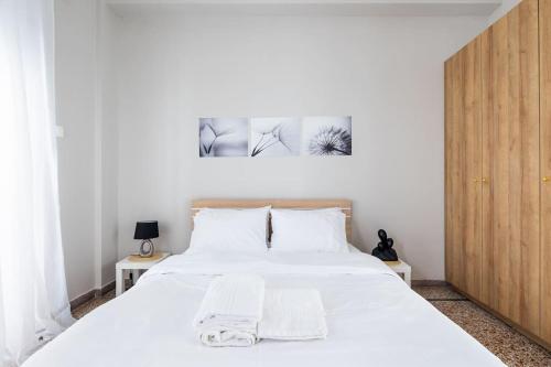 um quarto com uma cama branca e duas fotografias na parede em Prestige apartment in the heart of Athens ( 1 ) em Atenas