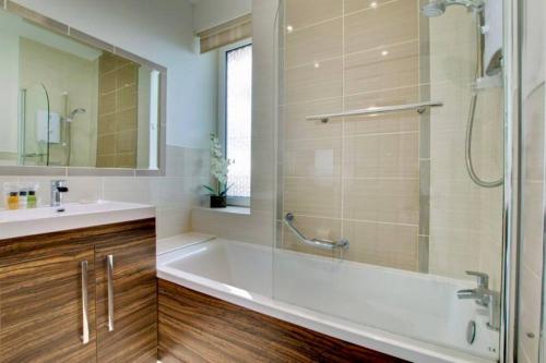 uma casa de banho com uma banheira, um chuveiro e um lavatório. em 180° Water View Apartment - Simply Amazing em Torquay