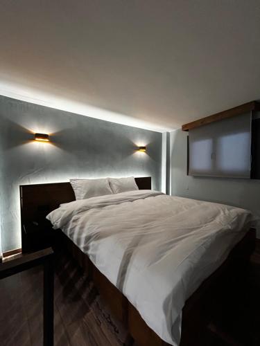 - une chambre avec un grand lit blanc et deux lumières dans l'établissement Wooden Suites, à Thessalonique