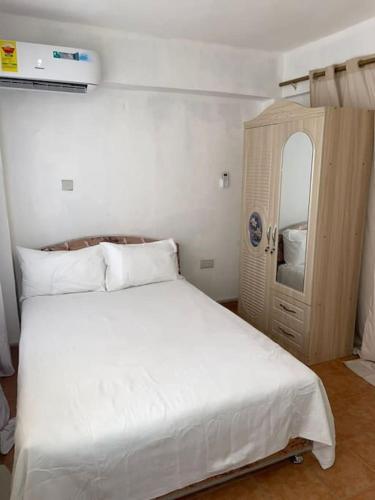 a bedroom with a white bed and a wooden cabinet at The Lord's residence in Tema