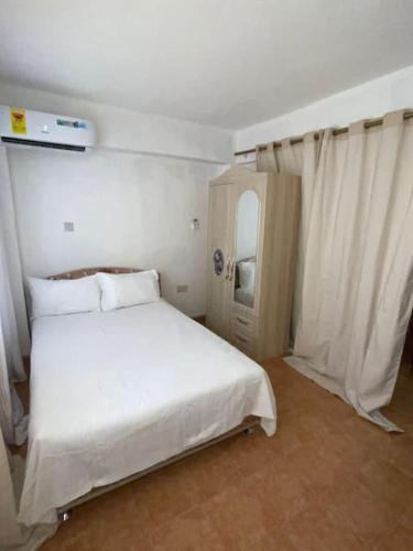 a bedroom with a white bed and a mirror at The Lord's residence in Tema