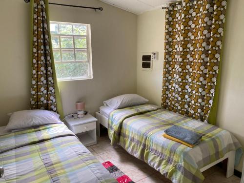 twee bedden in een kleine kamer met een raam bij Sucasa apartement in Willemstad