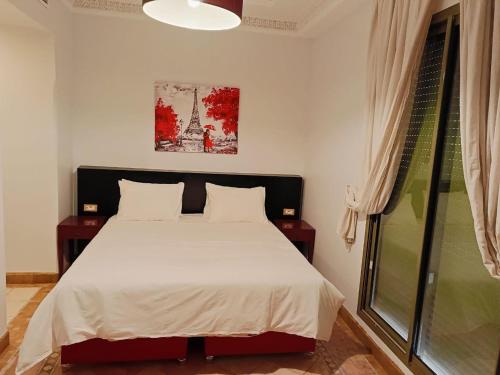 Schlafzimmer mit einem Bett und einem Fenster in der Unterkunft Appartements de charme à la palmeraie in Marrakesch