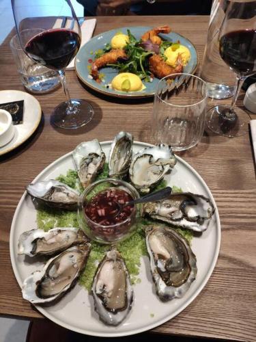 une assiette d'huîtres sur une table avec des verres de vin dans l'établissement Les Coquelicots, à Honfleur