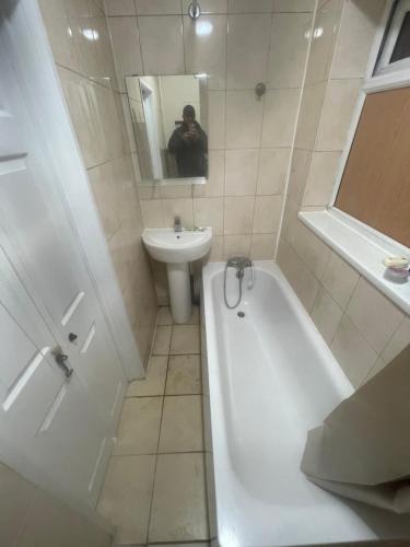 a man taking a picture of a bathroom with a tub and sink at 11 Chalvey Road east sl12ll in Slough