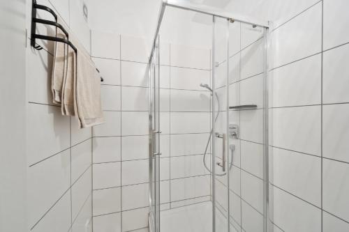 La salle de bains est pourvue d'une douche et de carrelage blanc. dans l'établissement Ruhige Lage, gute Anbindung, frisch renoviert, à Fellbach