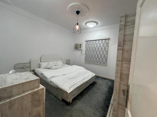 Habitación blanca con cama y lámpara de araña. en شقة العقيق عروة alaqeeq apartments en Medina