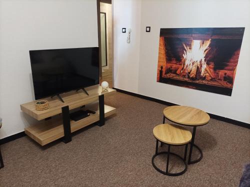 a living room with a flat screen tv and two stools at Au doux refuge in Zimmersheim