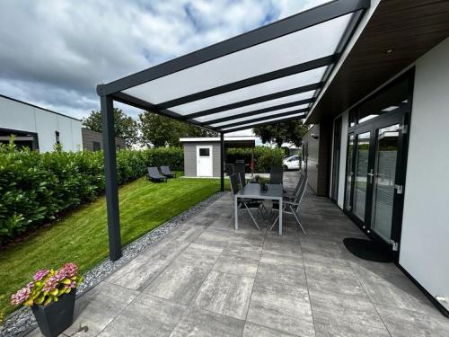a patio with awning and a table and chairs at Ferienhaus / Chalet / Bungalow am See, Holland, Niederlande, Lathum in Lathum
