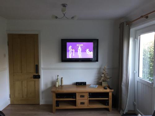 a living room with a tv on the wall at Hollyhocks in Saint Minver