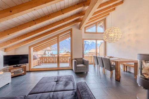 a living room with a dining room table and a large window at Chalet Apartments Iseltwald in Iseltwald