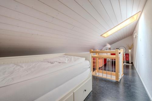 a white room with a bed and a book shelf at Chalet Apartments Iseltwald in Iseltwald