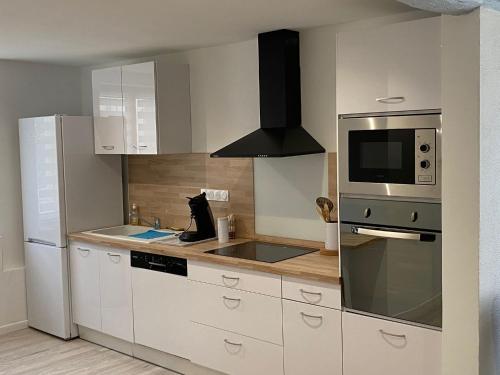 une cuisine avec des armoires blanches, un évier et un micro-ondes dans l'établissement L'Aréna - Logement cosy proche des arènes, à Nîmes