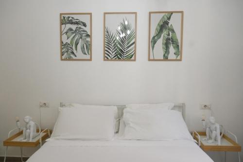 a bedroom with a white bed with three pictures on the wall at Roman Forum Holiday Termini in Rome