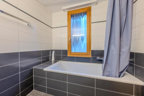 a bathroom with a tub and a window at Chalet Apartments Iseltwald in Iseltwald
