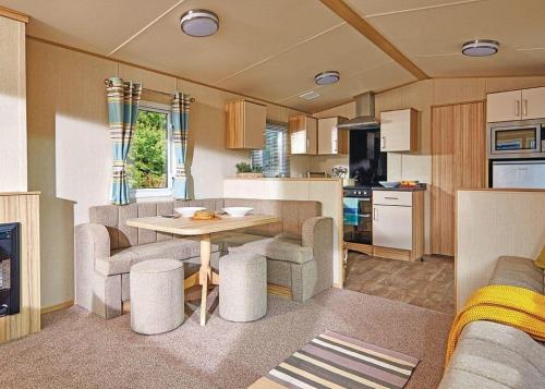 een keuken en een woonkamer met een tafel in een caravan bij White Tower Holiday Park in Llandwrog