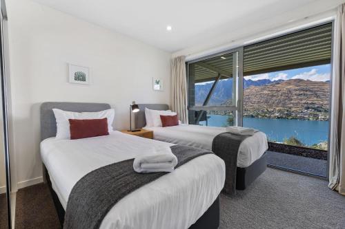 two beds in a room with a large window at Remarkable Views on Goldrush in Queenstown