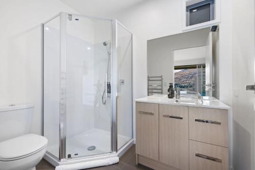a white bathroom with a shower and a toilet at Remarkable Views on Goldrush in Queenstown