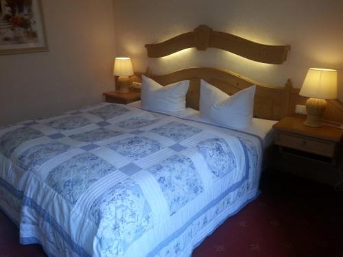 a bedroom with a blue and white bed with two lamps at Hotel und Restaurant Sackwitzer Mühle in Bad Schmiedeberg