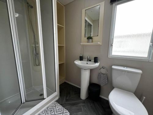 y baño con aseo, lavabo y ducha. en Lovely 8 Berth Caravan At Highfield Grange In Essex Ref 26213o, en Clacton-on-Sea