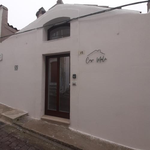 a white building with a door and the words one white at Casa MaLù 15 Cin I T 0 7 1 0 3 3 B 4 0 0 0 8 8 3 3 2 in Monte SantʼAngelo