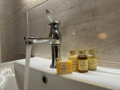 a sink with a faucet and three jars of honey at The Coach House in Chedworth