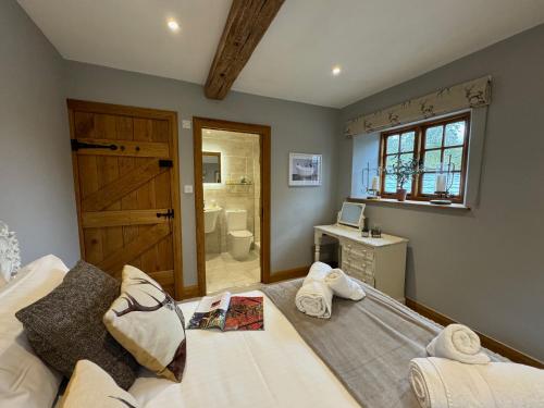 1 dormitorio con 1 cama grande y baño en The Coach House en Chedworth