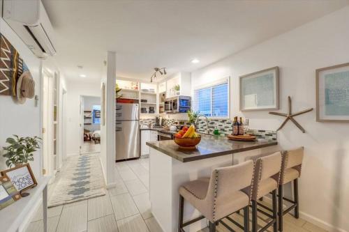 a kitchen with white walls and a island with bar stools at Ocean View Blue Mission Beach Paradise in San Diego