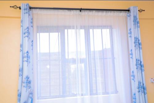 una ventana con cortinas azules y blancas en una habitación en Nuri Homes, en Kisii