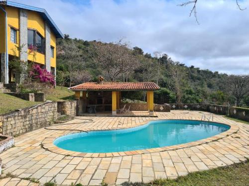 a swimming pool in front of a house at Sitio Ramalhete - Sua escapada perfeita na Serra da Mantiqueira in São Bento do Sapucaí