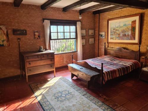 a bedroom with a bed and a dresser and a window at Sitio Ramalhete - Sua escapada perfeita na Serra da Mantiqueira in São Bento do Sapucaí