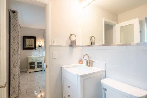 a white bathroom with a sink and a mirror at Wilton Manors Cottage West 2 Bed 2 Bath With Pool in Fort Lauderdale
